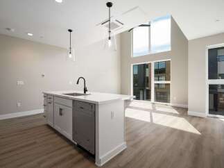 Experience modern living in this stunning kitchen featuring a sleek island with a built-in sink and contemporary faucet.