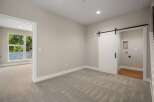 Discover modern living in this spacious room featuring a stylish white barn door leading to a laundry area.