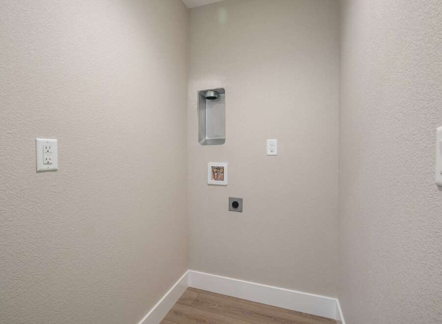 This laundry room is equipped with essential hookups for your washer and dryer, including a dedicated dryer vent and water connections.