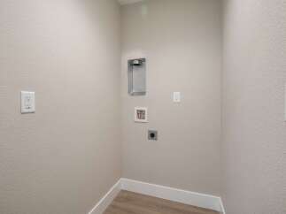 This laundry room is equipped with essential hookups for your washer and dryer, including a dedicated dryer vent and water connections.