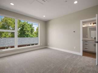 Step into this beautifully appointed bedroom featuring a large picture window that floods the space with natural light and offers serene views of lush greenery.