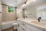 This modern bathroom features a sleek white vanity with dual sinks and black fixtures, complemented by a spacious bathtub and toilet.