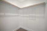 Discover ample storage in this spacious walk-in closet, featuring sturdy wooden rods and white shelving brackets.