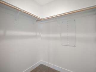 Discover ample storage in this spacious walk-in closet, featuring sturdy wooden rods and white shelving brackets.