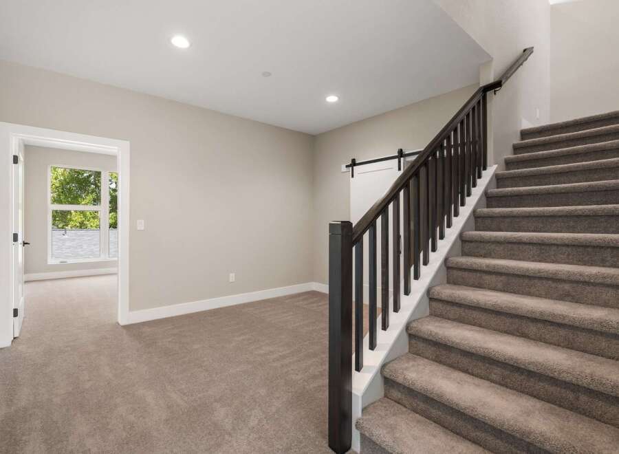 Step into this beautifully designed home featuring a grand staircase with dark wood railings and plush carpeting.