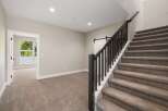 Step into this beautifully designed home featuring a grand staircase with dark wood railings and plush carpeting.