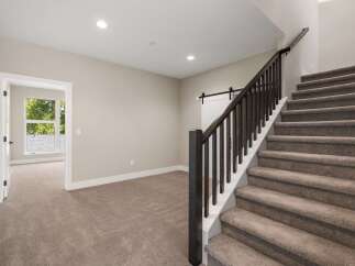 Step into this beautifully designed home featuring a grand staircase with dark wood railings and plush carpeting.