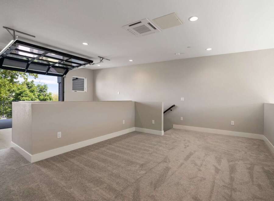 Experience modern living in this spacious loft-style room featuring a unique glass garage door that opens to a scenic outdoor view.