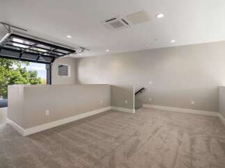Experience modern living in this spacious loft-style room featuring a unique glass garage door that opens to a scenic outdoor view.