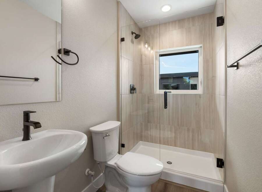 This modern bathroom features a sleek pedestal sink with a waterfall faucet and a stylish toilet.