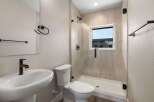 This modern bathroom features a sleek pedestal sink with a waterfall faucet and a stylish toilet.