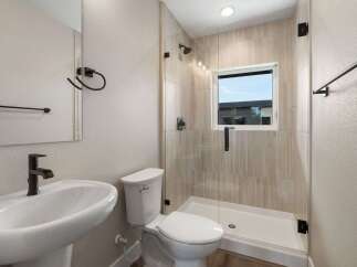 This modern bathroom features a sleek pedestal sink with a waterfall faucet and a stylish toilet.