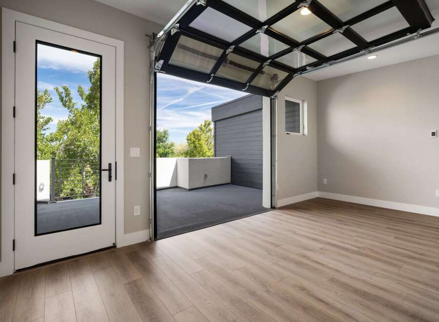 Experience modern living with this stunning property featuring a unique glass garage door that opens to a spacious outdoor deck, perfect for entertaining or enjoying the fresh air.
