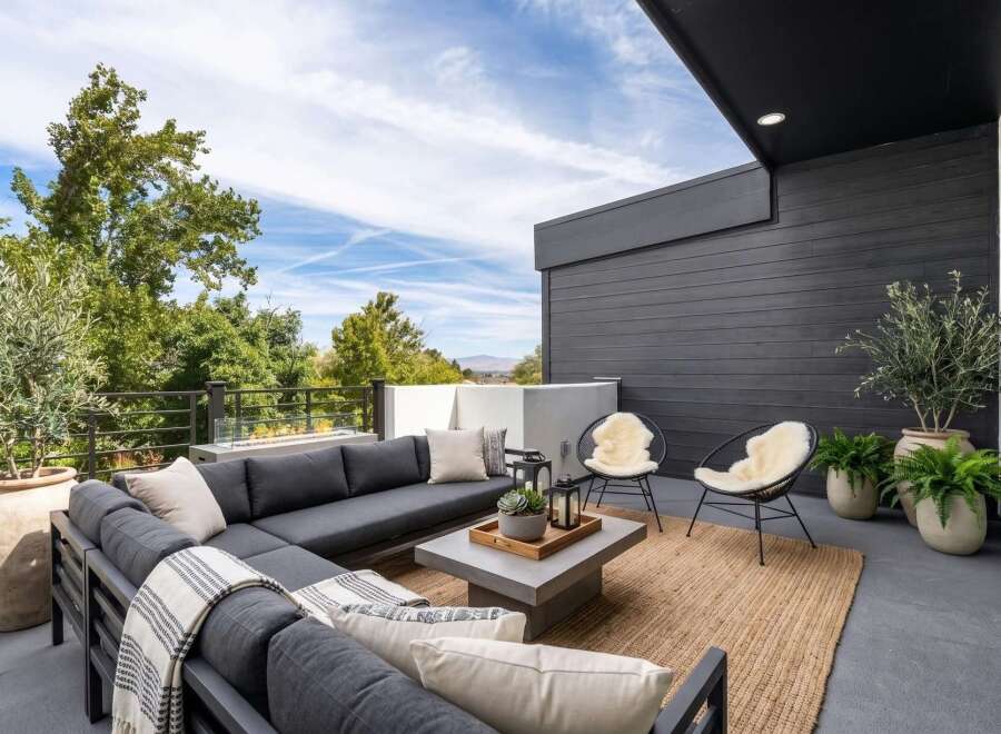 Experience luxurious outdoor living on this expansive modern patio, featuring a deep charcoal sectional sofa perfect for entertaining.