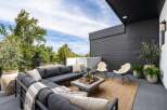 Experience luxurious outdoor living on this expansive modern patio, featuring a deep charcoal sectional sofa perfect for entertaining.
