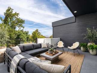 Experience luxurious outdoor living on this expansive modern patio, featuring a deep charcoal sectional sofa perfect for entertaining.