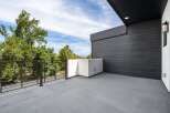 Experience modern living with this stunning balcony, featuring sleek dark wood siding and a minimalist white planter.