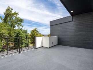 Experience modern living with this stunning balcony, featuring sleek dark wood siding and a minimalist white planter.