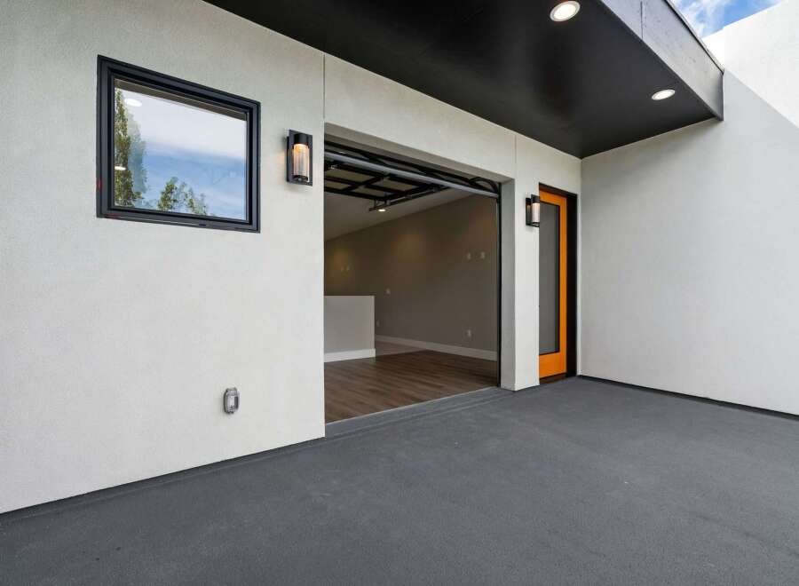 Discover modern living with this property's sleek exterior featuring a dark grey patio and a striking orange-accented door.