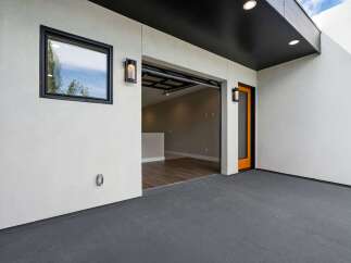 Discover modern living with this property's sleek exterior featuring a dark grey patio and a striking orange-accented door.