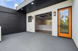 Discover modern living with this stunning property featuring a sleek black wood-paneled exterior and a bright, open-concept interior accessible through a striking orange-framed glass door.