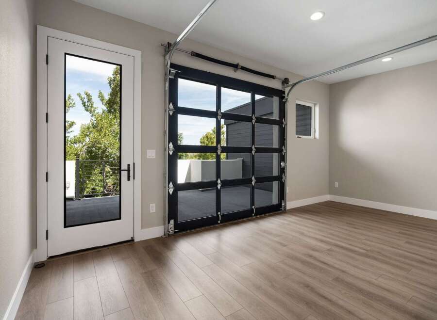Experience modern living with this stunning garage featuring a sleek glass garage door that floods the space with natural light.
