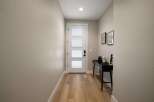 Step into this welcoming entryway featuring a modern white door with frosted glass panels, offering a glimpse of the natural light within.