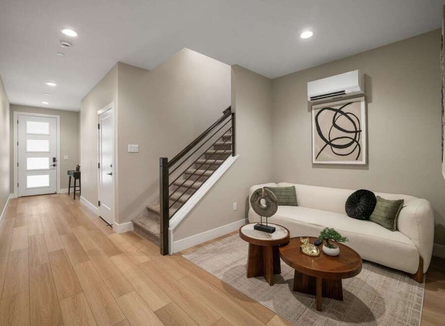 Step into this inviting living space featuring a stylish white sofa adorned with decorative pillows and a modern abstract artwork.