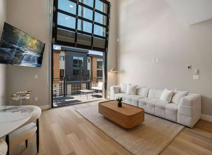 Experience modern living in this stunning apartment featuring a spacious open-concept living area with a large sectional sofa and a stylish coffee table.