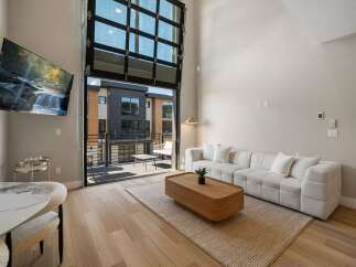 Experience modern living in this stunning apartment featuring a spacious open-concept living area with a large sectional sofa and a stylish coffee table.