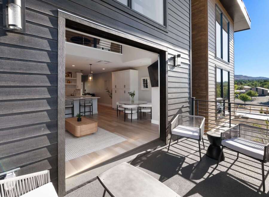 Experience seamless indoor-outdoor living with this modern home featuring a spacious balcony overlooking a scenic landscape.