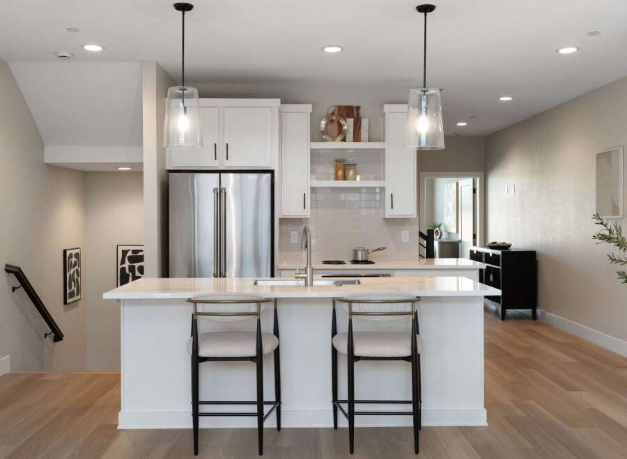 Experience modern living in this stunning kitchen featuring sleek white cabinetry, a spacious island with bar seating, and elegant pendant lighting.