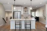 Experience modern living in this stunning kitchen featuring sleek white cabinetry, a spacious island with bar seating, and elegant pendant lighting.