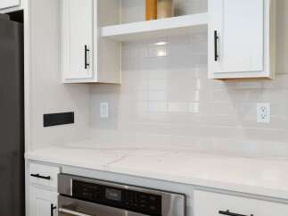 This modern kitchen features a sleek stainless steel oven and a smooth, white quartz countertop, perfect for meal preparation.
