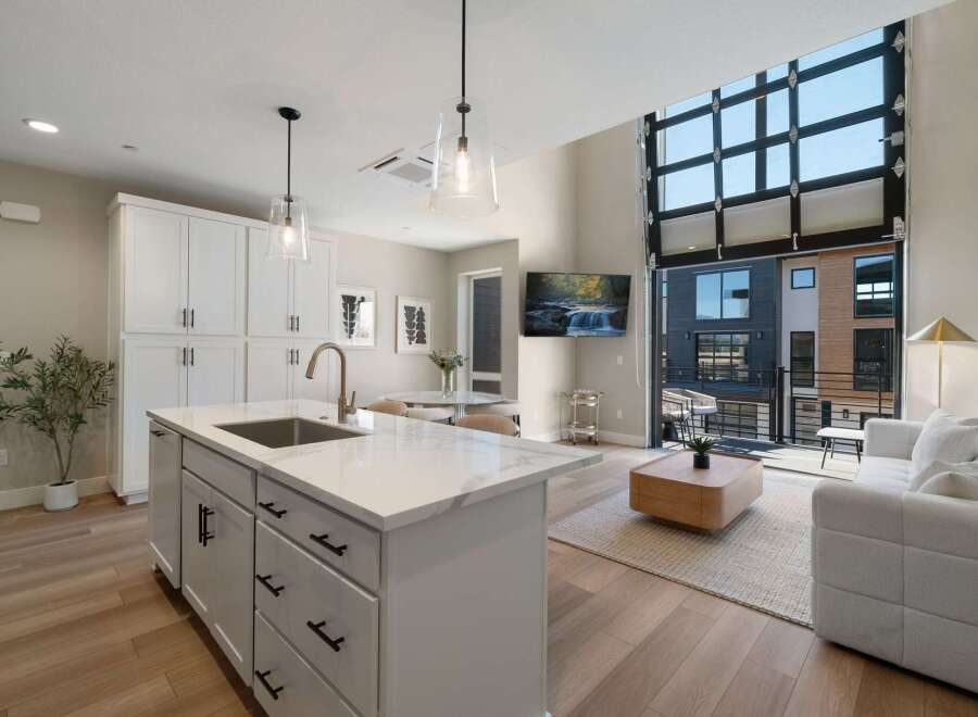 Experience modern living in this stunning open-concept space, featuring a sleek kitchen island with a waterfall countertop and a spacious living area.