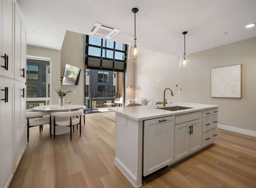 Experience modern living in this stunning open-concept space, featuring a sleek kitchen island with a waterfall countertop and a stylish dining area.