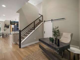 Step into a modern entryway featuring a sleek staircase with a dark metal railing and carpeted stairs.