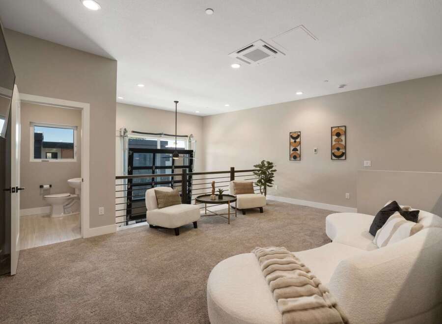 Discover this modern loft space featuring a stylish living area with plush seating and a unique curved sofa, perfect for relaxation.