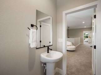 This modern bathroom features a sleek pedestal sink with a black faucet, complemented by a black towel rack holding plush white towels.
