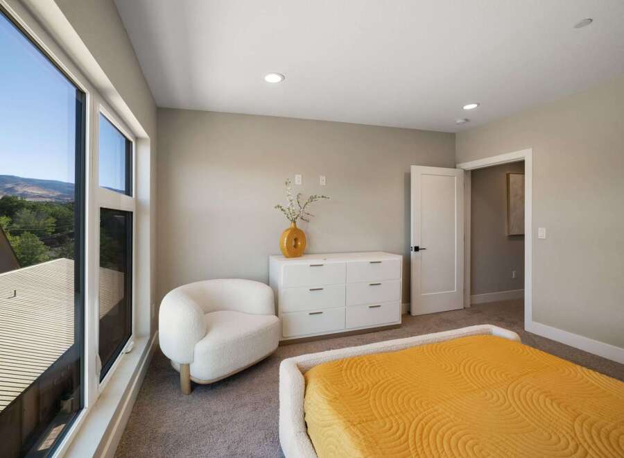 Experience modern comfort in this inviting bedroom, featuring a plush white armchair and a sleek white dresser.