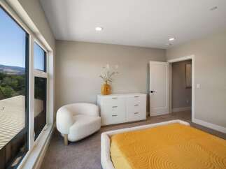 Experience modern comfort in this inviting bedroom, featuring a plush white armchair and a sleek white dresser.