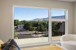 Experience breathtaking mountain views from this stunning property, framed by a large, modern window.