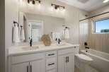 This modern bathroom features a spacious double vanity with white quartz countertops and sleek black fixtures.