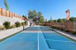 Enjoy outdoor recreation on this vibrant blue pickleball court, complete with a net and surrounding green and gray playing areas.