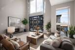 Experience modern living in this stunning living room featuring soaring ceilings and a dramatic floor-to-ceiling glass garage door that opens to the outdoors.