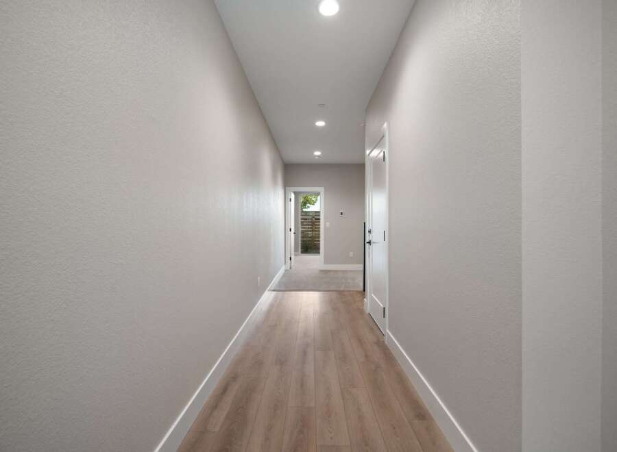 Step into this inviting hallway featuring a modern aesthetic with light gray textured walls and a sleek wooden floor.