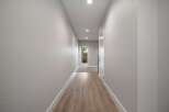 Step into this inviting hallway featuring a modern aesthetic with light gray textured walls and a sleek wooden floor.