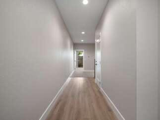Step into this inviting hallway featuring a modern aesthetic with light gray textured walls and a sleek wooden floor.