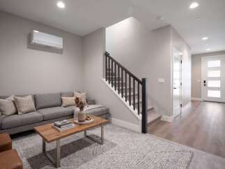 Step into this inviting living space featuring a comfortable grey sectional sofa adorned with plush throw pillows, perfect for relaxation.