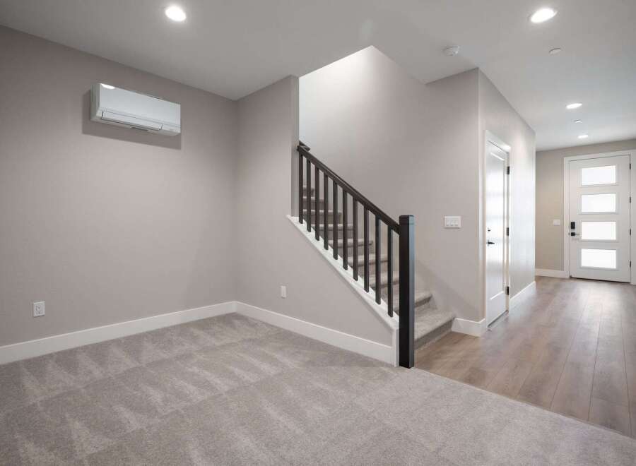 Step into this modern home featuring a spacious living area with plush carpeting and a convenient split AC unit for year-round comfort.